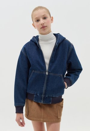 Donkerblauwe denim hoodie met rits, een capuchon, voorzakken, geribbelde marineblauwe manchetten en een iets cropped snit, gecombineerd met een beige corduroy rok.