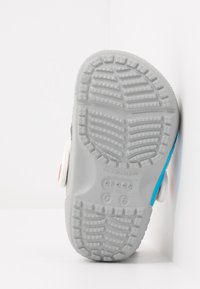 Gray rubber sole with textured grip pattern, white side accents, and blue detailing. Designed for comfort and durability.