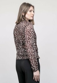 Blouse à imprimé animal marron avec poignet boutonné, en tissu lisse et léger, à manches longues et avec un col classique.