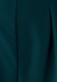 Blåtøjsstof med en glat tekstur og let glans, der har diagonale vævemønstre og blød fald, som primært viser indviklede folder.