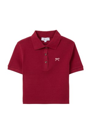 Rotes Poloshirt aus Baumwolle mit einem Kragen, drei braunen Knöpfen und einem kleinen gestickten Bogen auf der linken Brust. Kurze Ärmel, gerippte Textur.