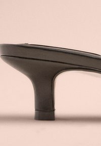Schwarze Absatzsandale mit einem glatten synthetischen Obermaterial, offenes Zehendesign und einem klobigen, verjüngten Absatz. Strukturierte Oberfläche mit minimalistischem Styling.