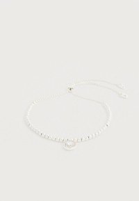 Sidabrinė karoliukų chokerio grandinėlė su centrine pakabuko detale, kurioje yra dekoratyvus apskritas dizainas ir subtilūs brangakmenių akcentai. Reguliuojamo ilgio grandinėlės detalės.