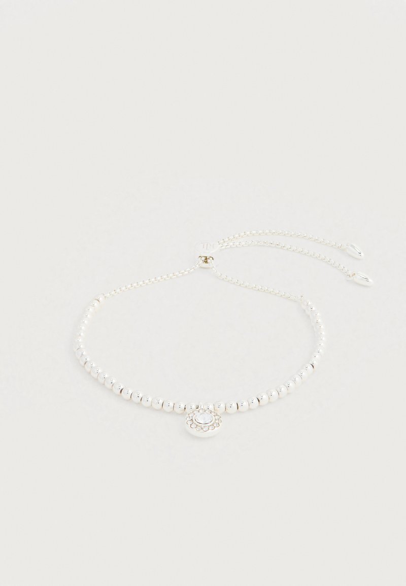 Sidabrinė karoliukų chokerio grandinėlė su centrine pakabuko detale, kurioje yra dekoratyvus apskritas dizainas ir subtilūs brangakmenių akcentai. Reguliuojamo ilgio grandinėlės detalės.