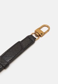 Mustekki nahkainen hihna, jossa on kudottu kuvio, varustettuna kultaisella metalliklipsillä ja tarvikkeilla kiinnittämistä varten.