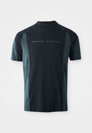 Majica kratkih rokavov Nike Tech, z temno mornarsko telesom in svetlo teal stranskimi paneli ter visokim ovratnikom. Logotip natisnjen spredaj.