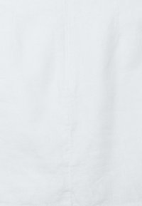 Valkoinen pellavakangas, jossa on sileä rakenne ja hienovarainen kiilto. Keskellä pystysuora sauma rakenteellisena yksityiskohtana.