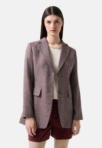 Blazer s houndstooth vzorem, který se vyznačuje strukturovaným střihem, dvěma knoflíky, klopami a bočními kapsami. Barevné schéma zahrnuje burgundské a krémové tóny.