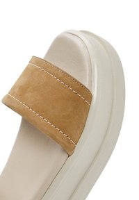 Sandalo slip-on in suede marrone chiaro con una fascia larga, caratterizzato da cuciture bianche e una suola testurizzata avorio per garantire aderenza.