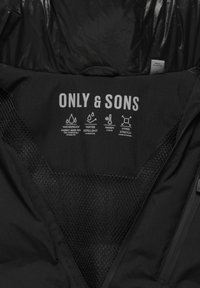 Black waterproof jacket with a smooth texture. Features include mesh lining, zip closure, and printed labels for waterproofing and flexibility.