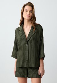 Loungewear-Set aus einem Baumwollgemisch in Dunkelgrün, mit einem strukturierten, gestreiften Muster, kurzen Ärmeln und einem kurzärmeligen Hemd mit passenden Shorts.