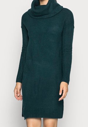 Vestido de suéter tejido en color azul verdoso con cuello de cisne, mangas acanaladas y dobladillo. Textura suave, longitud hasta el muslo y aberturas laterales para mayor comodidad de movimiento.