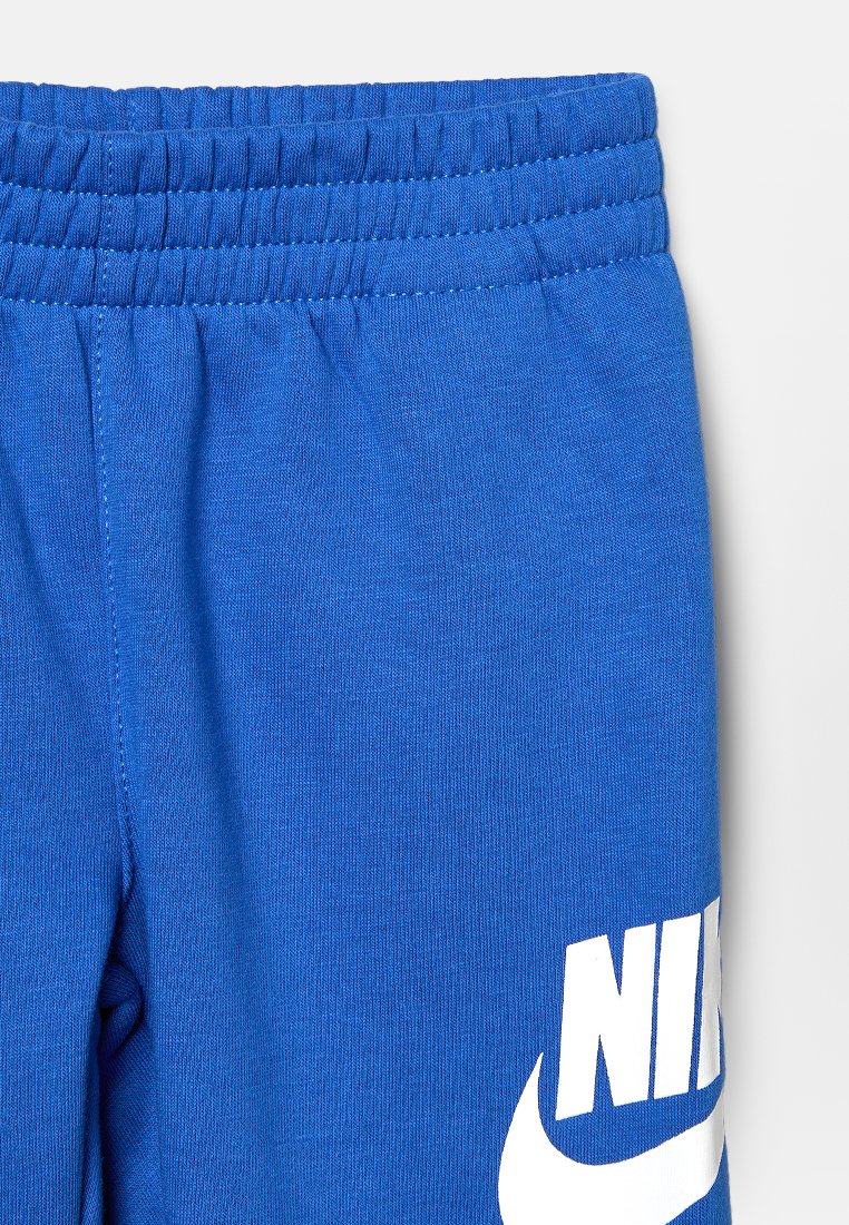 Pantaloni sportivi blu Nike con cintura elastica e logo Nike bianco visibile sulla coscia destra.