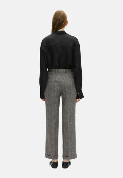 Top lungo a maniche nere in satin abbinato a pantaloni larghi a quadri grigi. I pantaloni presentano orli arrotolati e una vestibilità sartoriale. Inclusi scarpe nere a ballerina.