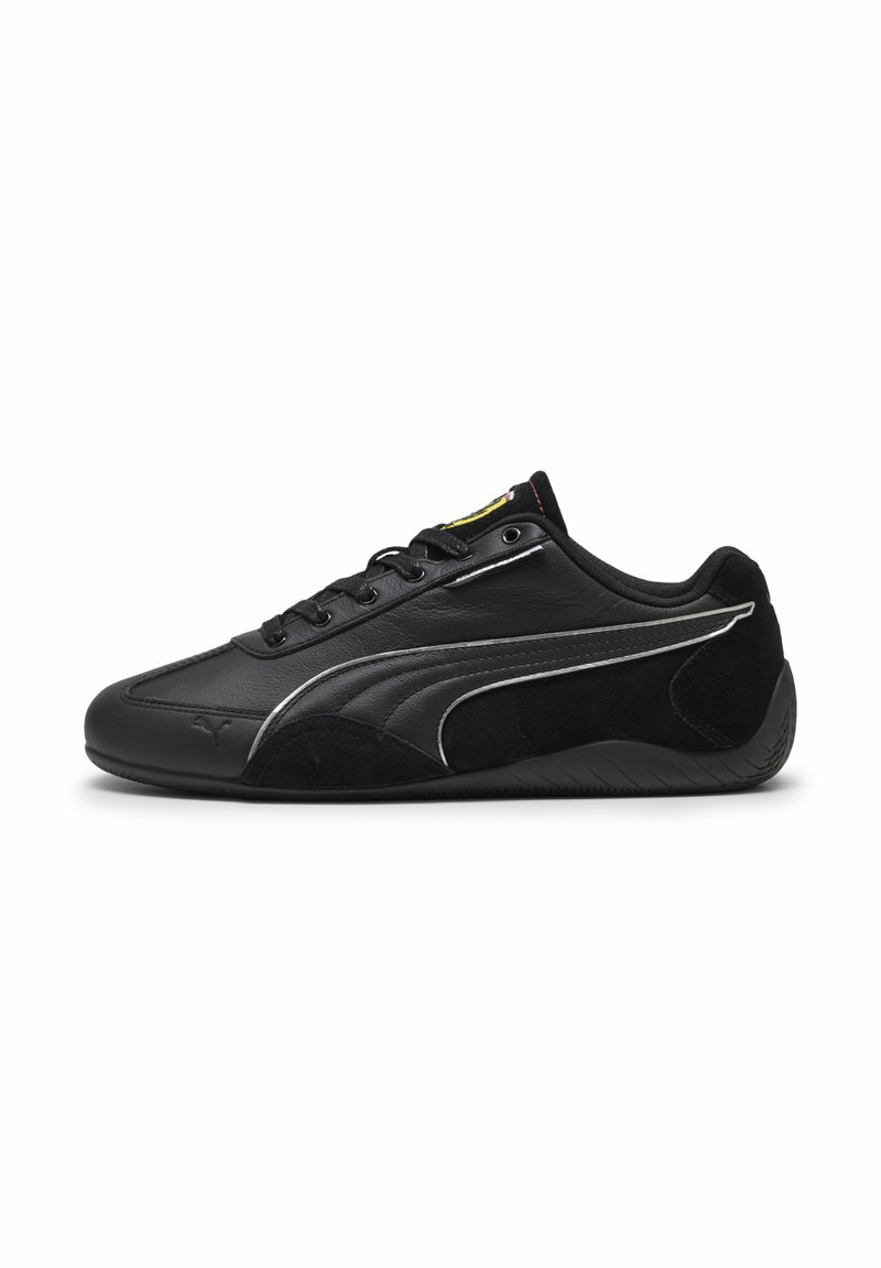Zapatilla deportiva negra que presenta una combinación de cuero liso y ante, con un diseño elegante, cordones y una suela de goma texturizada.