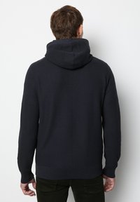 Navy blue hoodie, knitted texture, long sleeves, adjustable drawstring, and ribbed cuffs. Back view shows hood and seam details.