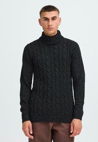 Maglione a collo alto in lana a trecce color carbone con orlo e colletto a coste spesse, caratterizzato da motivi strutturati e maniche lunghe.