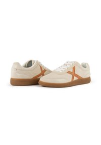 Sneaker in suede beige con dettagli arancioni, suola in gomma testurizzata, punta tonda e lacci bianchi. Design minimalista con logo sulla parte posteriore.
