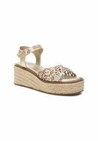 Sandalo wedge metallizzato oro con suola in espadrillas intrecciata, dotato di una fascia decorativa di perline e di un cinturino alla caviglia con fibbia.