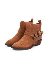 Botas de tobillo de ante marrón con punta afilada, detalle acanalado en la parte superior y correa con hebilla. Cuenta con un tacón bajo y apilado para mayor estabilidad.