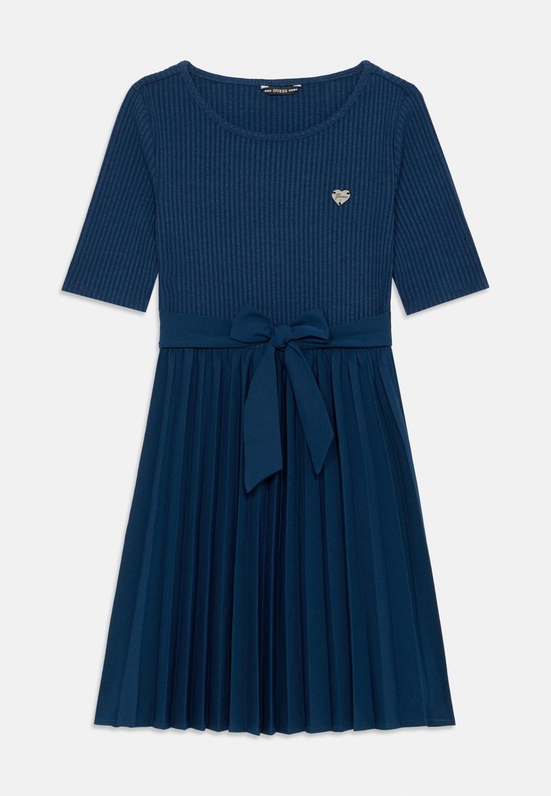 Robe bleu marine avec haut côtelé, manches mi-longues, jupe plissée, nœud à la taille et petit logo en métal en forme de cœur sur la poitrine.