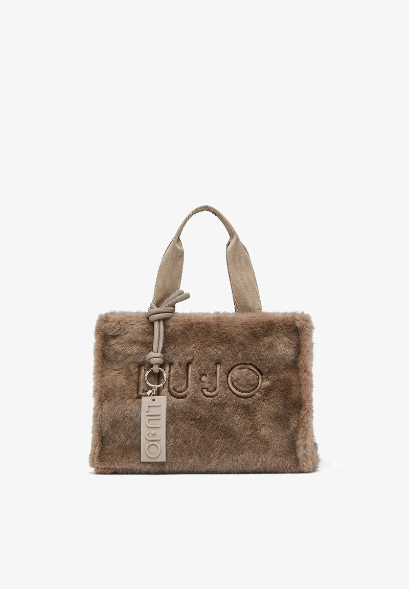 Sac à main rectangulaire marron en fausse fourrure avec poignées en tissu beige et une étiquette suspendue beige embossée du nom de la marque.
