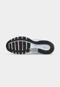 Σόλα αθλητικού παπουτσιού Nike με μαύρο, άσπρο και κόκκινο σχέδιο σε λευκό φόντο.