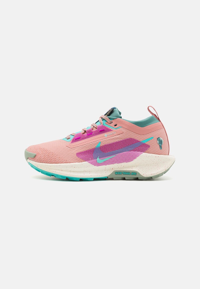 Les chaussures de course Nike Trail ATC présentent un dessus en textile rose avec des accents en aqua et violet, une semelle épaisse mouchetée blanche et un empiècement de talon renforcé.