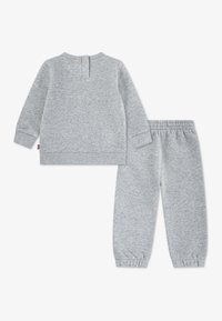 Σετ γκρι φούτερ και παντελόνι που ταιριάζουν. Το φούτερ έχει στρογγυλή λαιμόκοψη, μακριά μανίκια και ριμπ μανσέτες. Το παντελόνι διαθέτει ελαστική μέση.