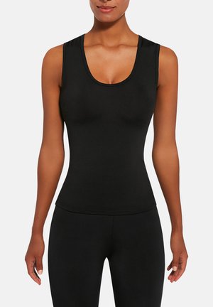 Kobieta ubrana w dopasowaną, czarną, bezrękawnikową bluzkę z dekoltem w łódkę oraz czarne spodnie, pokazana od ramion do bioder na jednolitym tle.