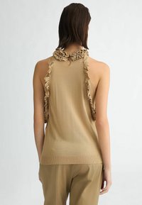 Top beige senza maniche con scollatura arricciata e dettaglio sul retro; tessuto a maglia testurizzato, design aderente, con apertura a chiave sul retro.