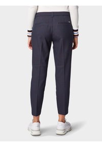 Spodnie w kratę w odcieniu granatowym o dopasowanym kroju, z bocznymi kieszeniami i gładką fakturą, zestawione z białymi butami sportowymi.