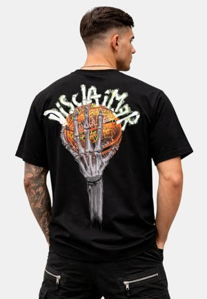 Uomo con capelli corti e braccio tatuato indossa una maglietta nera con una mano scheletrica che tiene una palla da basket e testo stilizzato sulla schiena.