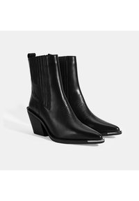 Bottines en cuir noir avec un bout pointu, surface texturée, tige côtelée et un talon empilé de hauteur moyenne. Accent en argent sur le bout.