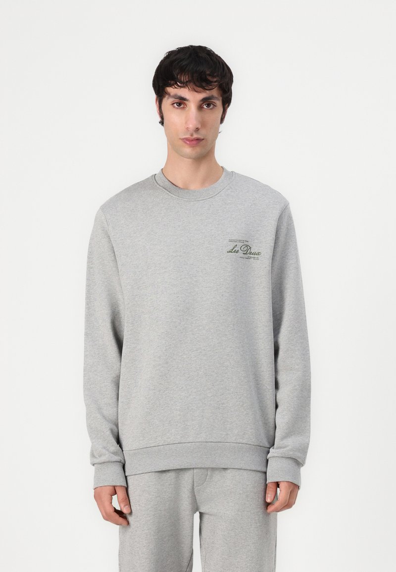 Sweatshirt gri din material moale, cu mâneci lungi, decolteu tip crew și un mic logo verde pe pieptul stâng.