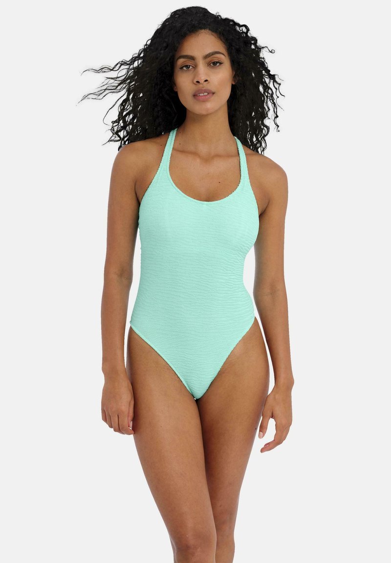 Maillot de bain une pièce vert menthe en tissu texturé, avec des jambes hautes et un col rond, doté de fines bretelles croisées dans le dos.