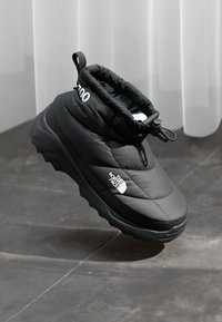 Juoda izoluota slidinėjimo batų pora su storu padu, elastingu kulkšnies apvalkalu, reguliuojamu troseliu ir "The North Face" logotipu šone.