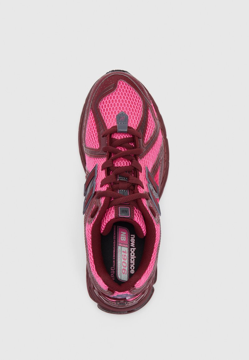 Pink mesh athletic shoe with maroon accents, featuring round laces and a cushioned interior. Branding visible on the tongue and insole.