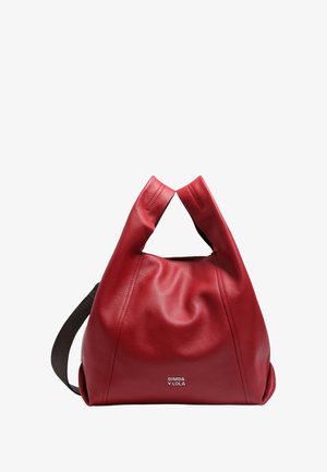 Rote Lederhandtasche mit einer lässigen Form, ausgestattet mit zwei runden Griffen und einem schwarzen Riemen; enthält ein metallisches Logo auf der Vorderseite.