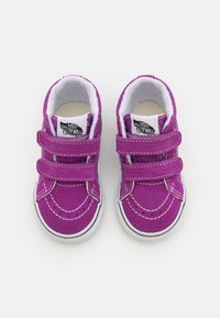 Lila Wildledersneaker mit weißen Nähten und Klettverschlüssen. Verfügt über eine weiße Gummisohle und ein schwarz-weißes Logo auf der Zunge.