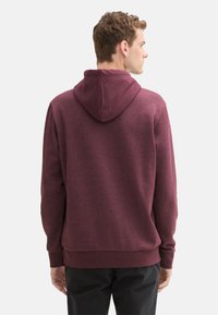 Bordeaux hoodie gemaakt van een textuurstof, met ribgebreeide manchetten en zoom. Eenvoudig ontwerp, zonder patronen, voorzien van een dubbele capuchon.