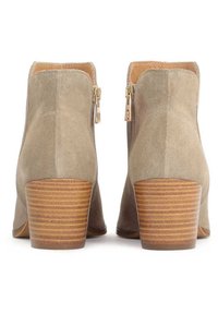 Botine din suede în taupe deschis, cu fermoare laterale duale, toc din lemn stratificat și o textură netedă. Au un design elegant și conic.