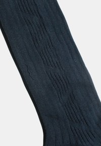 Tmavě modrá podkolenka sahající ke kolenu z texturované látky, s vertikálními žebrovanými vzory a hladkými částmi, s jemnými detaily po celém povrchu.