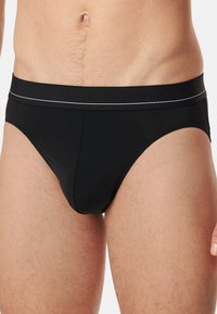 Sorte bomuldsunderbukser med en tætsiddende design, elastisk talje med et subtilt logo og lysegrå stikninger langs den øverste kant.