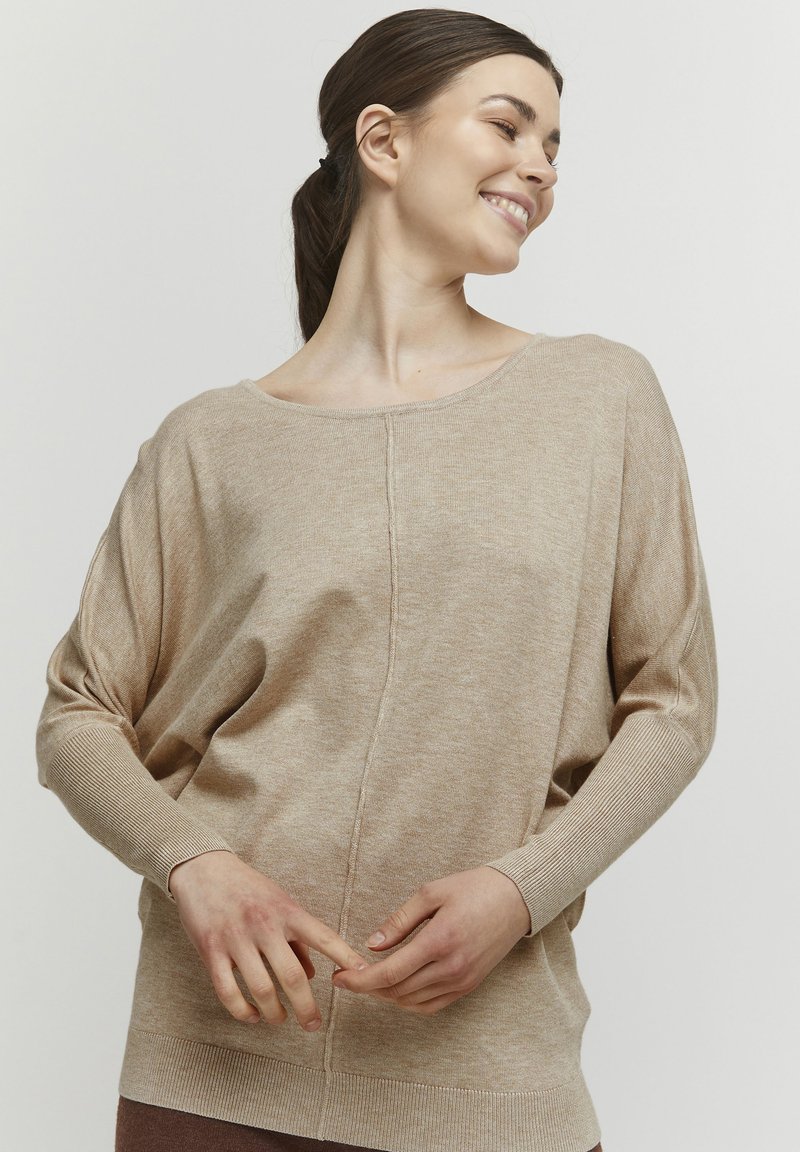 Beiger Strickpullover mit weitem, lockerem Halsausschnitt und überschnittenen Schultern. Verfügt über eine Mittelnaht und gerippte Bündchen für Textur und Detail.