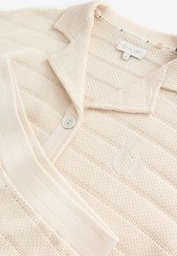 Beige Strick-Polohemd mit strukturiertem Diamantmuster, spitzem Kragen, einer Knopfleiste und besticktem Logodetail.