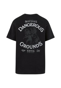 Sort bomulds T-shirt med korte ærmer, prydet med et grafisk motiv af to løver samt teksten: "FARLIGE TERRÆNER" og "OVERLEVELSE FOR DE FITTESTE" i hvid.