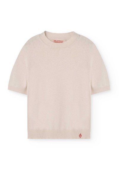 Suéter de manga corta y cuello redondo en suave lana beige. Presenta puños y dobladillo acanalados, con un pequeño acento de logo rojo en la parte inferior izquierda.