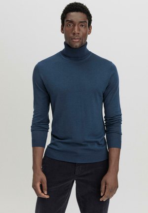 Blauwe coltrui van zacht breigoed, met lange mouwen en een getailleerd ontwerp, gecombineerd met donkere broek.