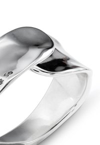 Anillo de plata con un acabado liso y pulido. Presenta un diseño curvado único que se superpone en la parte superior. Detalles grabados en la banda interior.